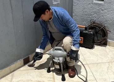 Coladera de azotea en un tercer piso, tapada por hojas y residuos de cabello de un perro, un profecional manipulando la maquinaria